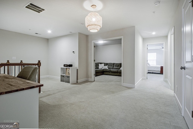 corridor featuring baseboards, visible vents, and light colored carpet