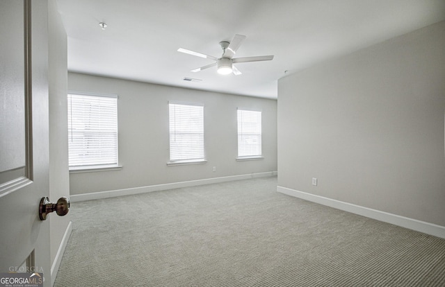 carpeted empty room featuring ceiling fan, visible vents, and baseboards