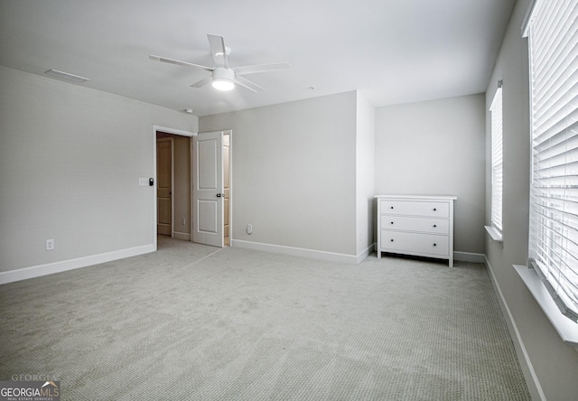 unfurnished bedroom with light colored carpet, baseboards, and multiple windows