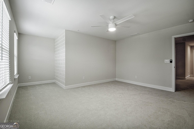 unfurnished room featuring a wealth of natural light, light carpet, ceiling fan, and baseboards