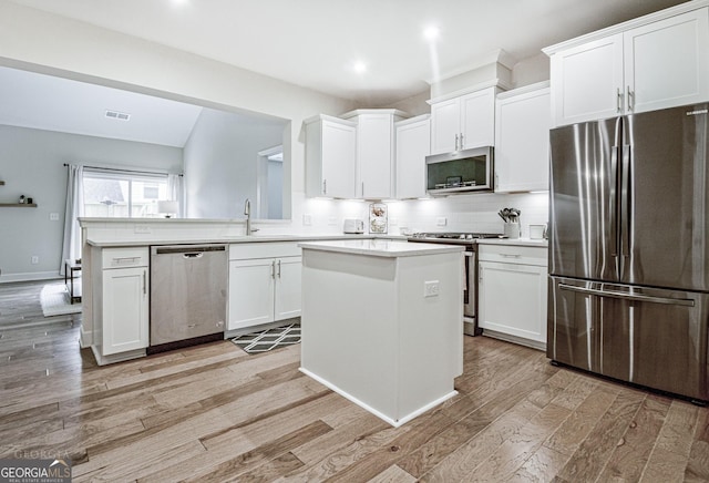 kitchen featuring light wood finished floors, tasteful backsplash, appliances with stainless steel finishes, and white cabinets