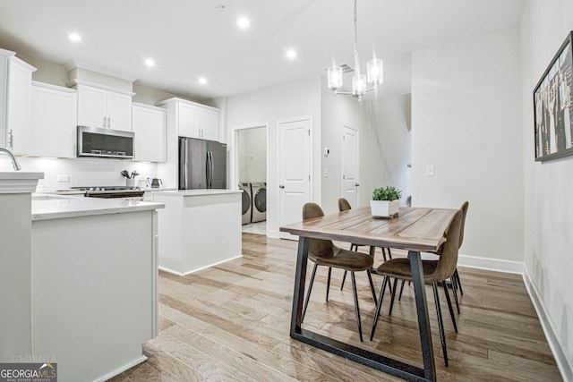 kitchen featuring stainless steel appliances, light countertops, independent washer and dryer, light wood finished floors, and tasteful backsplash