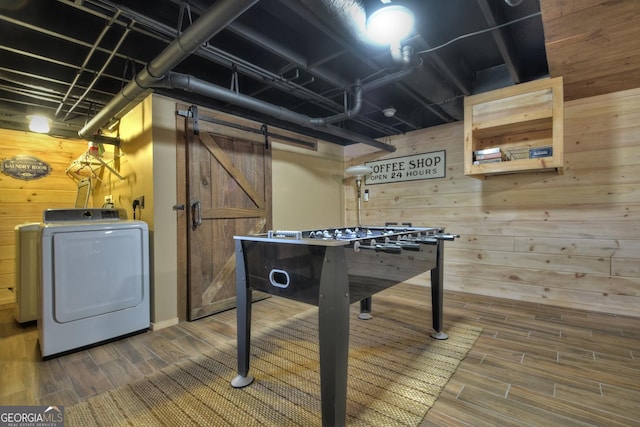 game room with washer / clothes dryer, a barn door, wood walls, and wood tiled floor