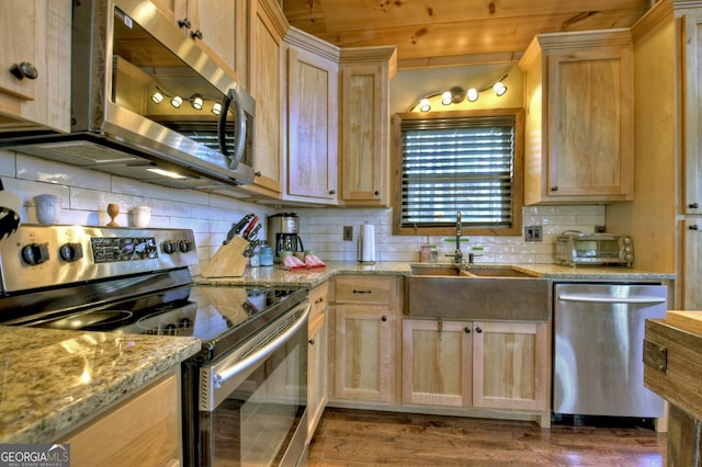 kitchen with stainless steel appliances, light brown cabinetry, backsplash, and a sink