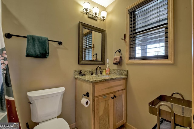 bathroom featuring toilet, baseboards, and vanity