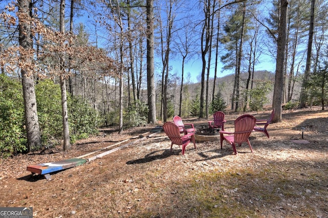 view of yard with a fire pit and a wooded view