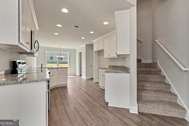 kitchen featuring electric stove, wood finished floors, visible vents, and white cabinets