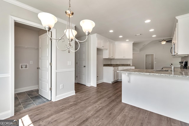 kitchen featuring appliances with stainless steel finishes, dark wood-style flooring, a peninsula, white cabinetry, and ceiling fan with notable chandelier