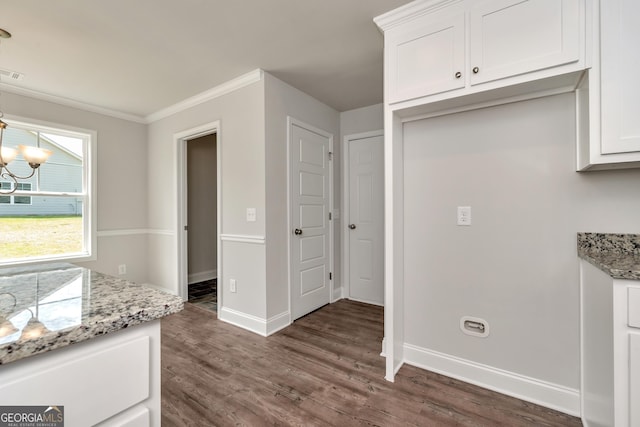 kitchen with white cabinets, light stone counters, dark wood-type flooring, and a notable chandelier