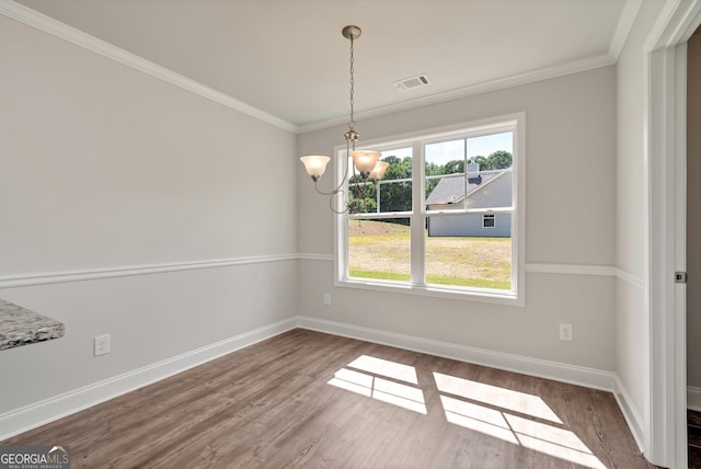 unfurnished dining area with a wealth of natural light, crown molding, visible vents, and wood finished floors