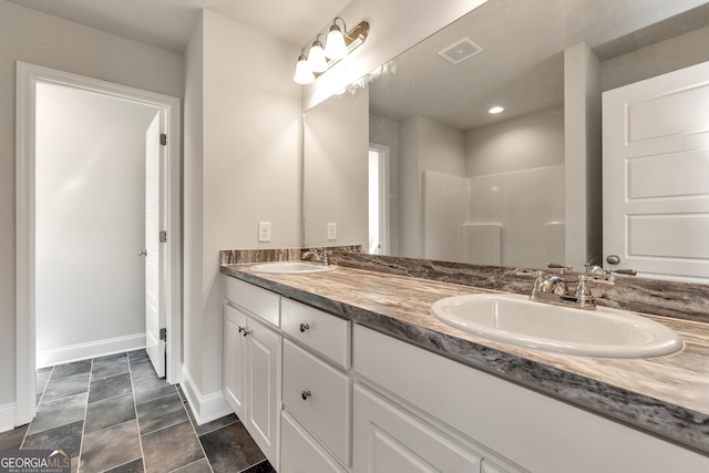 bathroom featuring double vanity, baseboards, visible vents, and a sink