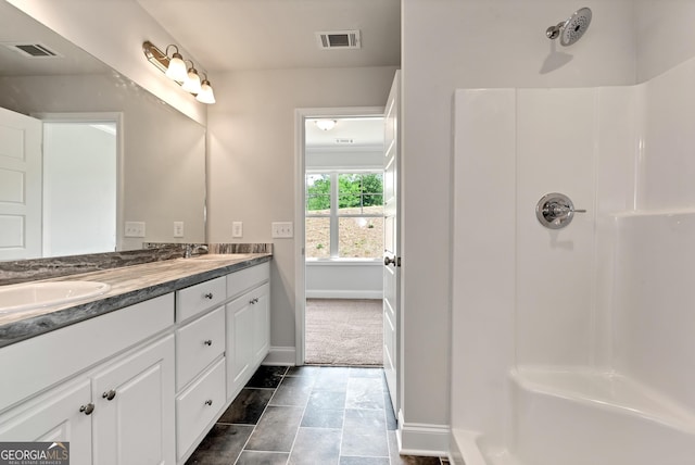 full bath featuring double vanity, visible vents, a sink, and walk in shower