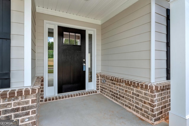 doorway to property with covered porch and brick siding