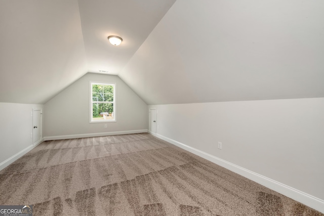 additional living space featuring carpet flooring, vaulted ceiling, and baseboards