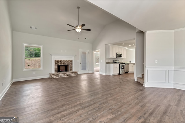 unfurnished living room featuring visible vents, dark wood-style floors, ceiling fan, a brick fireplace, and a decorative wall