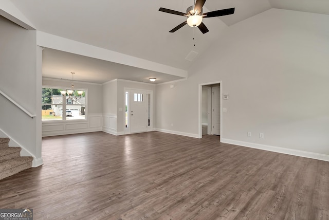 unfurnished living room with a wainscoted wall, stairs, dark wood finished floors, and ceiling fan with notable chandelier