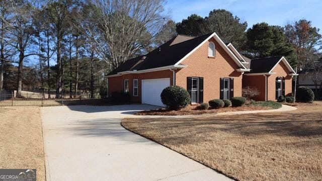 view of home's exterior featuring driveway, an attached garage, fence, and brick siding