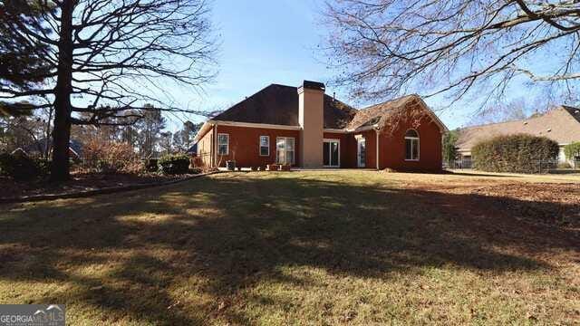 rear view of property featuring a yard and a chimney