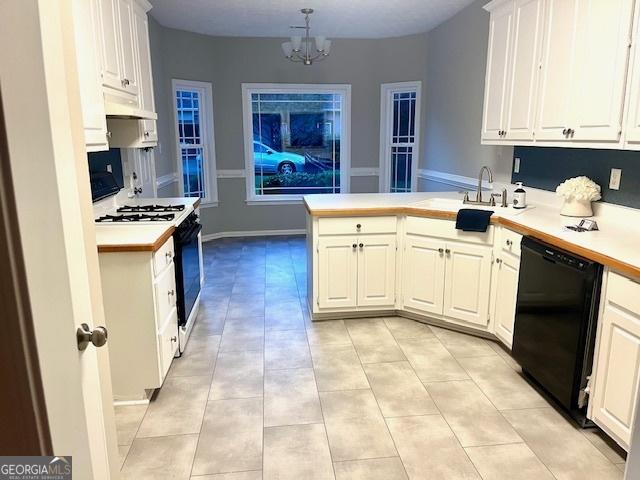 kitchen featuring dishwasher, a peninsula, light countertops, white cabinetry, and gas stove