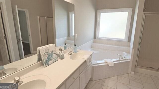 full bath with double vanity, a garden tub, a shower stall, and a sink