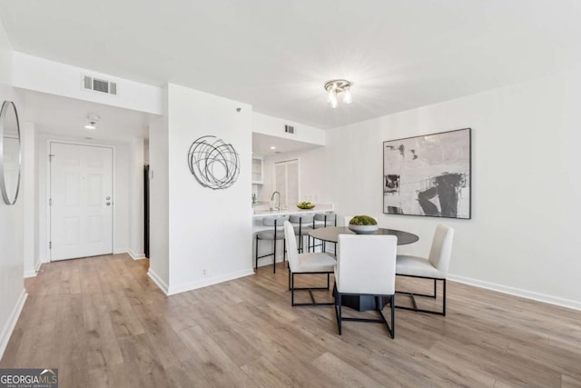 dining area with baseboards, visible vents, and wood finished floors