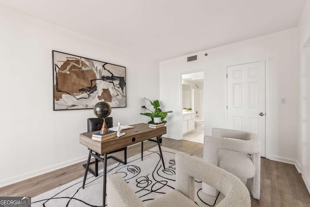 home office with baseboards, visible vents, and light wood finished floors