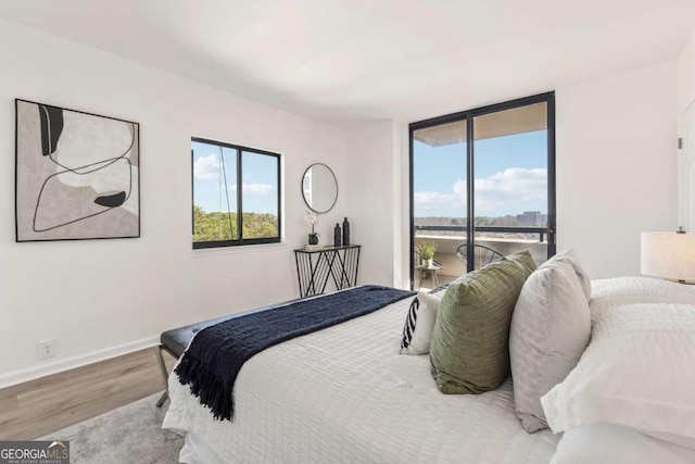 bedroom featuring access to outside, baseboards, and wood finished floors