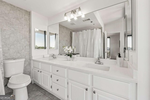 full bath featuring visible vents, toilet, a sink, and tile walls