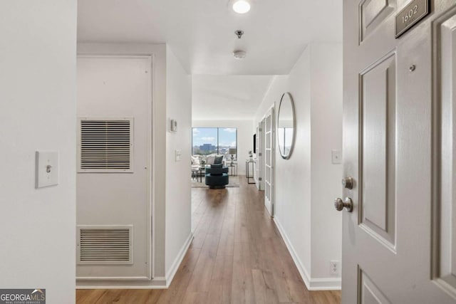 corridor with baseboards, visible vents, and light wood-style floors