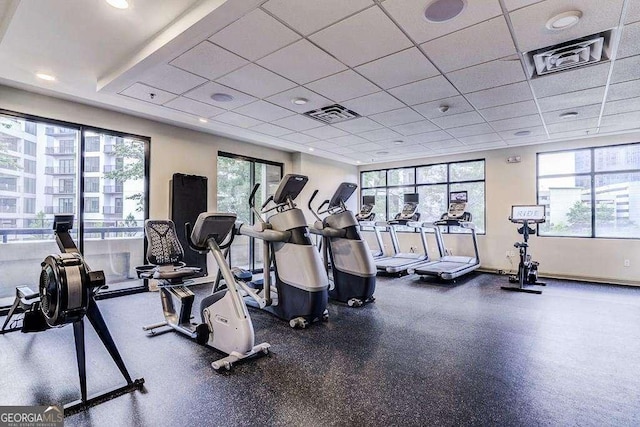 gym with a drop ceiling, visible vents, and a healthy amount of sunlight