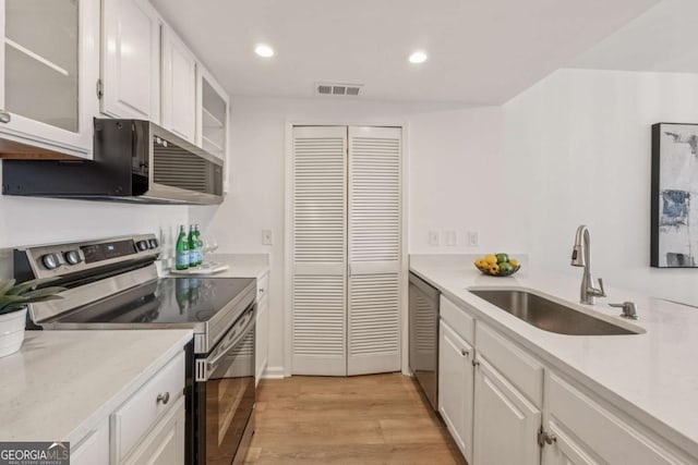 kitchen with a sink, visible vents, white cabinetry, light countertops, and appliances with stainless steel finishes