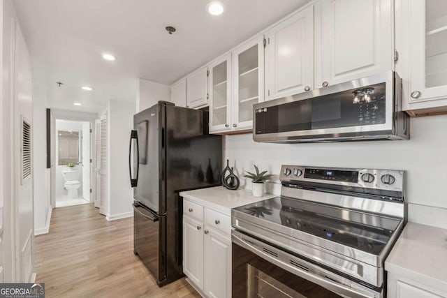 kitchen with light countertops, appliances with stainless steel finishes, light wood-type flooring, and white cabinetry