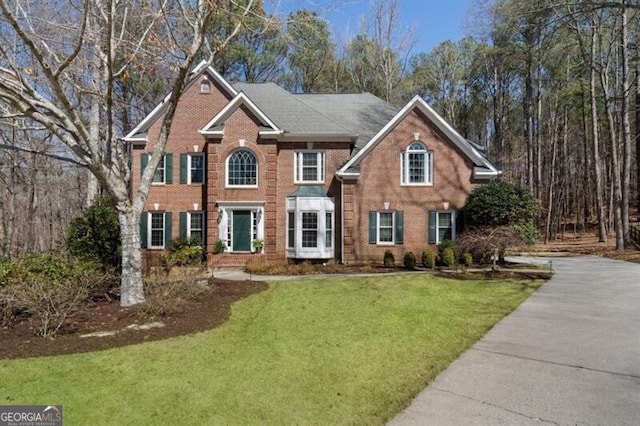 colonial inspired home with brick siding and a front yard