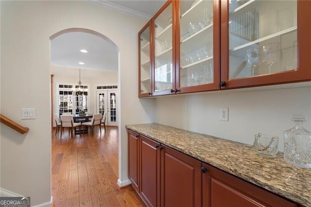 interior space with arched walkways, ornamental molding, wood finished floors, and baseboards