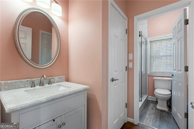 full bath with toilet, wood finished floors, vanity, baseboards, and a shower stall