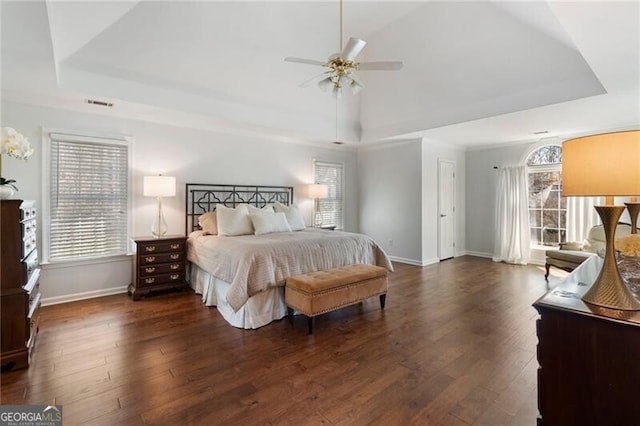 bedroom with baseboards, a raised ceiling, and dark wood finished floors