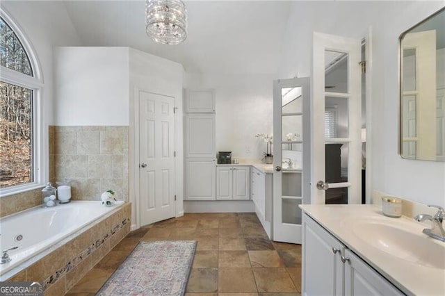 full bath with a chandelier, vanity, and a bath