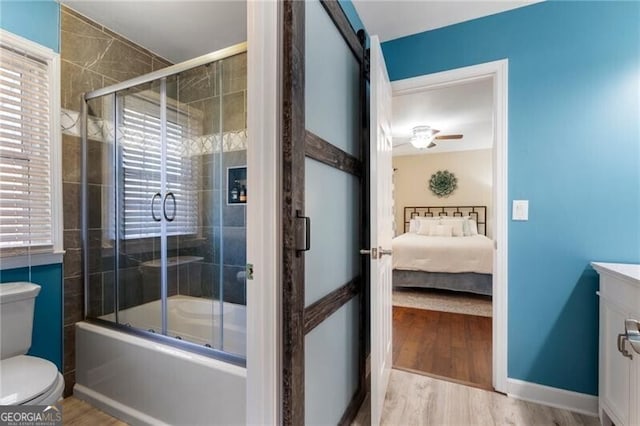 bathroom featuring toilet, shower / bath combination with glass door, wood finished floors, and vanity