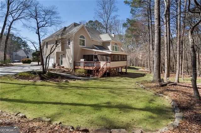 view of side of home featuring driveway, a sunroom, a lawn, and a chimney