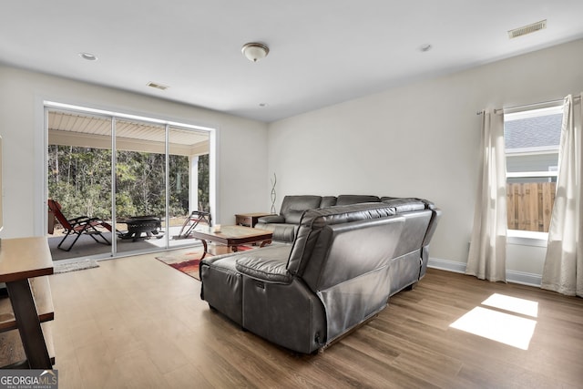 living room with a sunroom, wood finished floors, visible vents, and baseboards