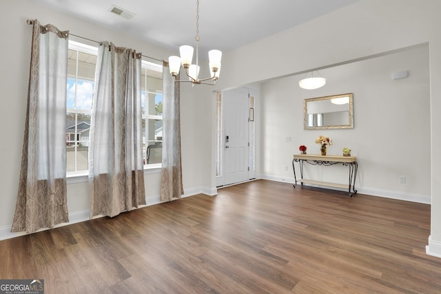 entrance foyer featuring an inviting chandelier, visible vents, baseboards, and wood finished floors