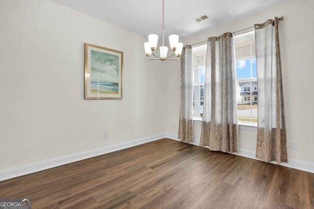 unfurnished room featuring visible vents, dark wood finished floors, baseboards, and an inviting chandelier