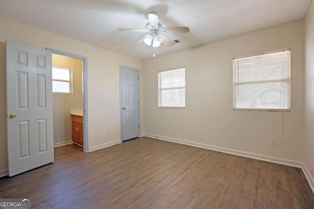 unfurnished bedroom with dark wood-style floors, multiple windows, and baseboards