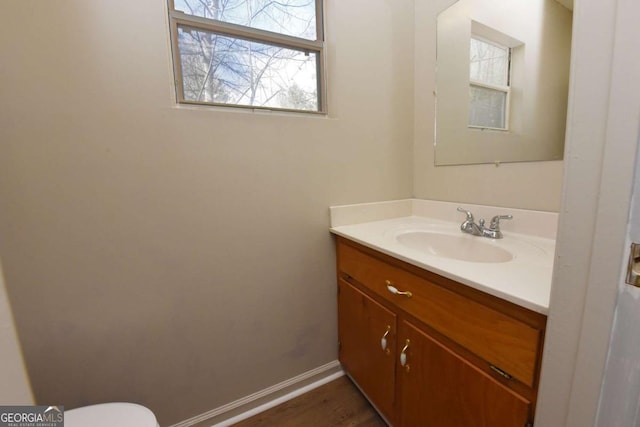 half bathroom with toilet, baseboards, and vanity