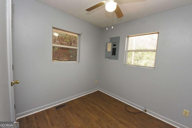 unfurnished room with dark wood-style floors, visible vents, ceiling fan, electric panel, and baseboards