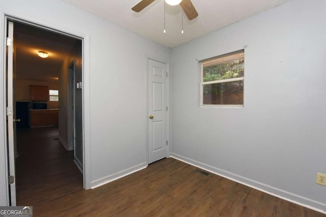 spare room featuring visible vents, baseboards, dark wood finished floors, and a ceiling fan