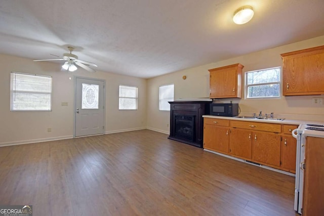 kitchen featuring white range with electric cooktop, wood finished floors, light countertops, black microwave, and a sink