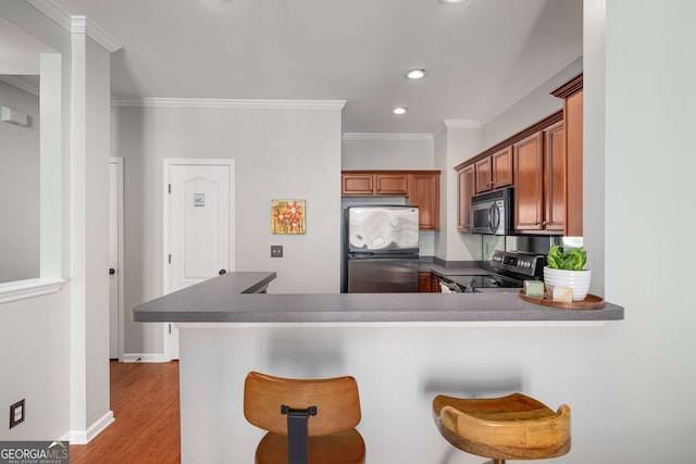 kitchen with a peninsula, appliances with stainless steel finishes, a kitchen bar, and crown molding