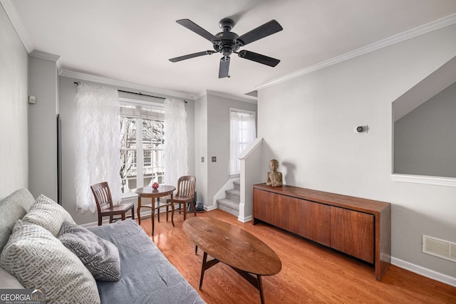 living area with visible vents, baseboards, light wood-style flooring, stairway, and crown molding