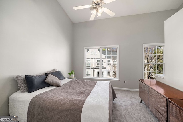 bedroom featuring a ceiling fan, light carpet, vaulted ceiling, and baseboards